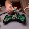 Löten am Controller Motherboard und hält eine Pinzette in der anderen Hand